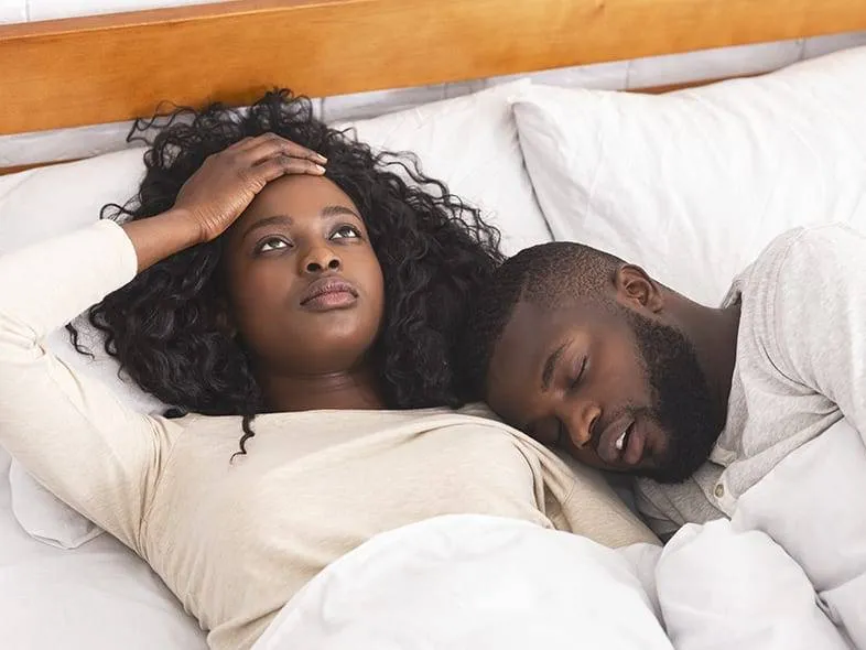 Woman lying awake beside a snoring partner